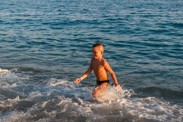 Fototapeta premium Seven-year-old tanned boy runs on water at sea