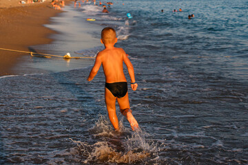 Fototapeta premium Seven-year-old tanned boy runs on water at sea