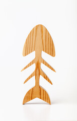 Figurine skeleton of a fish carved from solid pine by hand jigsaw. On a white background