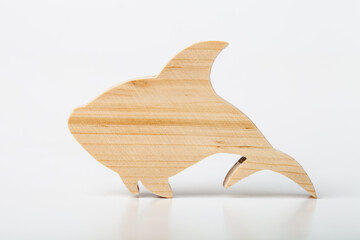 A figurine of a shark or fish, carved from solid pine with a hand jigsaw. On a white background