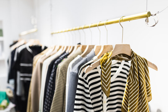 Row of different female clothes hanging on rack in hipster fashion show room in shopping mall. Trendy women wear