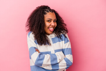 Young african american woman isolated on pink background funny and friendly sticking out tongue.