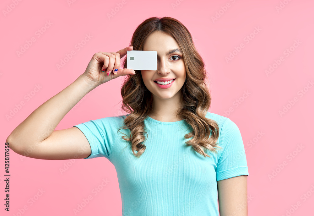 Wall mural Portrait of a pretty smiling woman holding credit card at her face - Wall murals