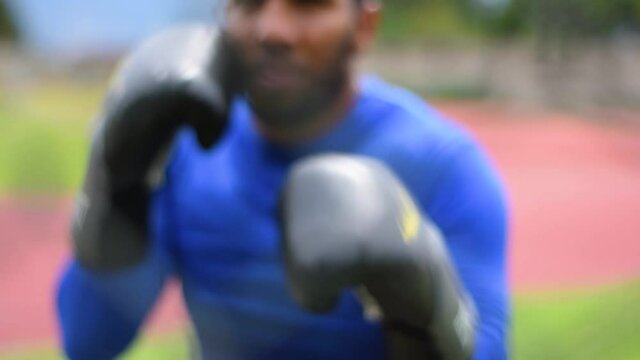 Hombre moreno con guantes de boxeo entrenando al aire libre rodeado de naturaleza
