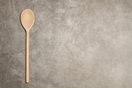 Cuchara de madera para cocinar sobre un fondo gris r&uacute;stico. Vista superior. Copy space