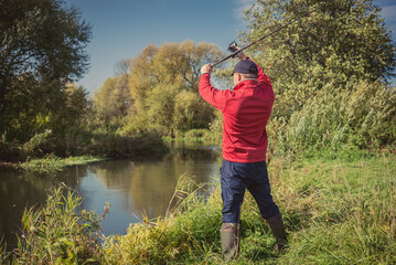 Fishermen fishing with a spinning rod from the shore on a sunny day. Fishing on a sunny day. Man on the river bank throws a spinning rod.