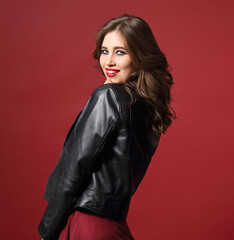 Fototapeta premium Beautiful fun happy young brunette woman in fashion black leather jacket on red background with empty copy space. Closeup