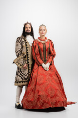Fototapeta premium full length of historical interracial couple in golden crowns and medieval clothing on white