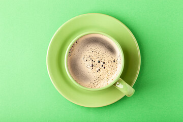 Hot fresh coffee with foam in the green cup on a color background