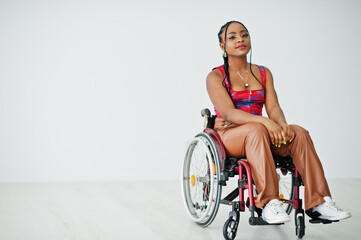 Young disabled African American woman in wheelchair against white wall. - Powered by Adobe