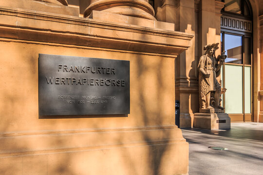 Entrance to the building with metal plaque of the German Stock Exchange in Frankfurt. Historic baroque house with arches, columns and figure. Steps in front of the glass entrance doors