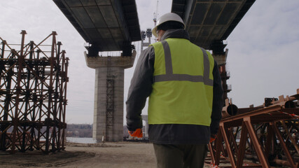 Male engineer walking under bridge