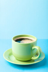 Hot fresh coffee with foam in the green cup on a color background