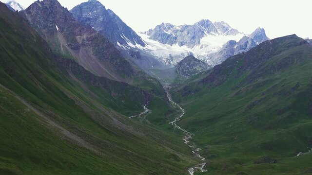 Alpine gorge is a magnificent panorama. View of the mountain river and snow-covered ridge and and Corrie glacier