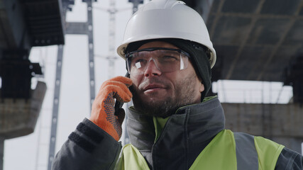 Male worker answering phone call under unfinished bridge