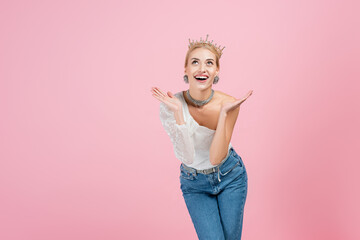 amazed blonde woman in luxury crown standing isolated on pink