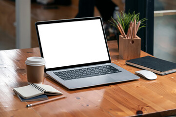 Blank screen laptop on wooden table in modern office.