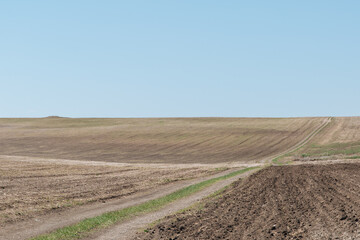 Fototapeta na wymiar Agricultural plowed field. Ploughing field. Arable land under the bright sky. Rural landscape. 
