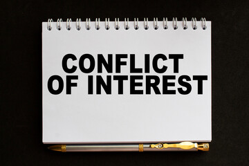 text CONFLICT OF INTEREST in notepad. office furniture on the table. business and finance