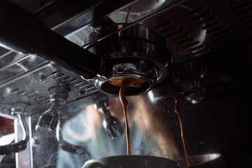 Espresso coffee pouring from machine in to the white cup .