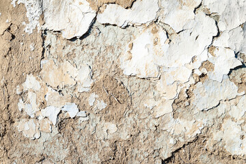 Old plastered wall background. The texture of the old peeling cracked, weathered plaster with chips and cracks. Collapsing clay wall. Destructive influence of time and environment.