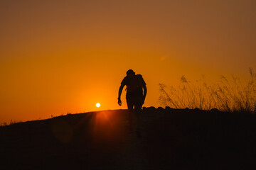 adventure travel from silhouette man hiking and stand on top of the mountain in summer season