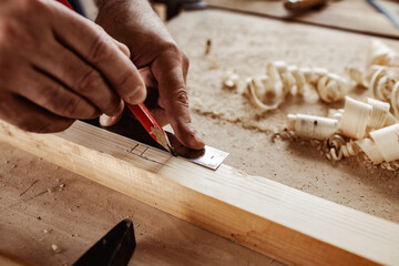 Carpenter makes pencil marks on a wood plank
