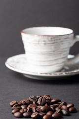 Roasted coffee beans and light cup on the black background. Shallow depth of field. Selected focuse