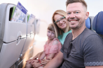 Smiling parents with child are sitting in aircraft cabin