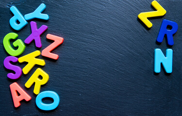 Frame from multicolored letters on black stone background. Topview. Copyspace. Concept back to school.