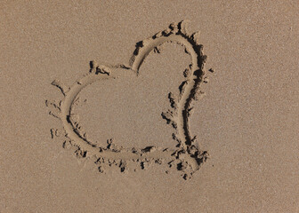 Heart is drawn on wet sand closeup