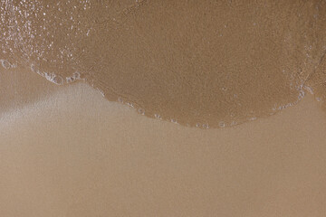 Beach with wet sand and water closeup
