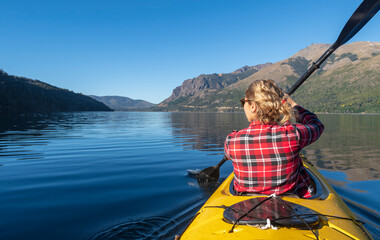 Beautiful woman enjoying her summer vacation kayaking through the lakes of Patagonia.