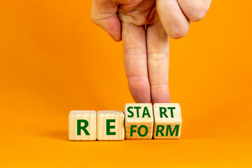 Restart and reform symbol. Businessman turns cubes and changes the word 'restart' to 'reform'. Beautiful orange background. Business and restart - reform concept. Copy space.