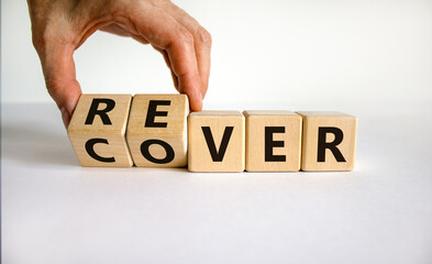 Recover symbol. Concept word 'recover' on wooden cubes on a beautiful white table. Businessman hand. White background. Business and recover concept. Copy space.