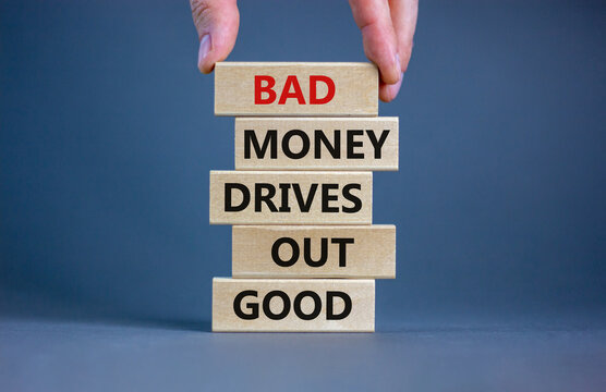 Business concept growth success process. Wood blocks on grey background, copy space. Businessman hand. Words 'bad money drives out good'. Conceptual image of motivation.