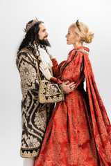 interracial king and queen in medieval clothing and crowns hugging isolated on white