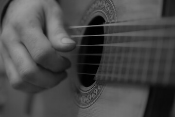 Black and white image of a hand of a man playing a classic  guitar