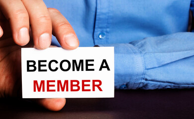 BECOME A MEMBER is written on a white business card in a man's hand. Advertising concept