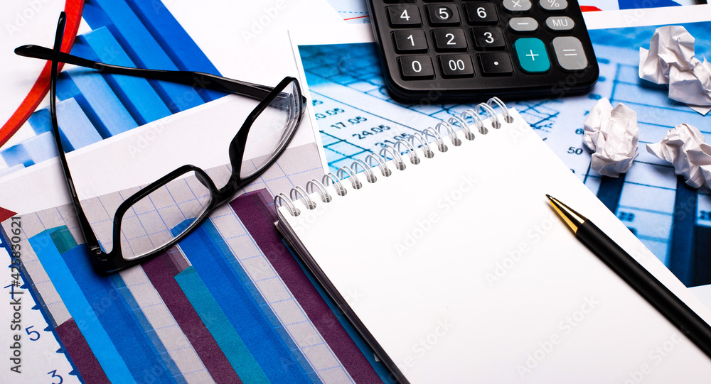Aufkleber against the background of documents and charts - a pen with a notebook, a calculator and glasses in 