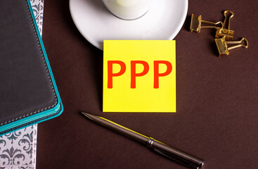 The word PPP Paycheck Protection Program written on yellow paper on a brown background near a...