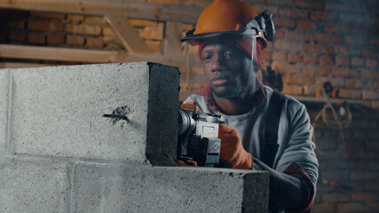 Serious black man drilling concrete block