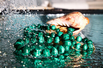Jewelry from green malachite. Malachite beads in the studio on a glass surface with water