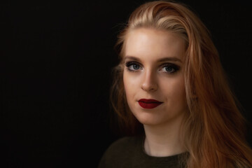 Low key portrait of smiling redhead young woman. Horizontally. 