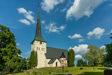 Summer view of an old white church with a cemetery in Sweden