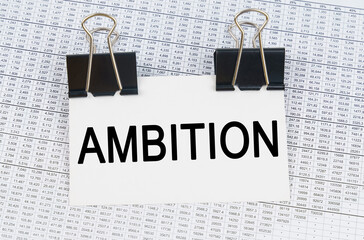 On the table there are reports and a business card with the inscription - AMBITION