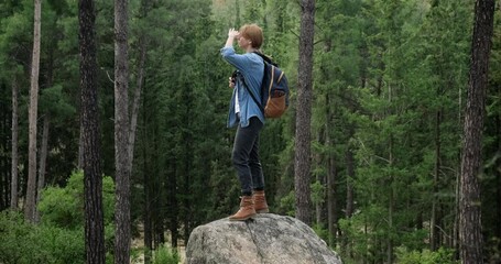 Traveler woman with backpack standing on huge rock in forest got lost and looking for direction to go.