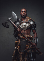 Wild african soldier wielding an axe and posing in dark background