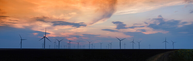 Colorful sunset landscape with wind turbine farm
