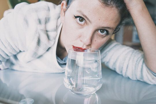 Portrait of a young woman hidden by a glass with a transparent drink